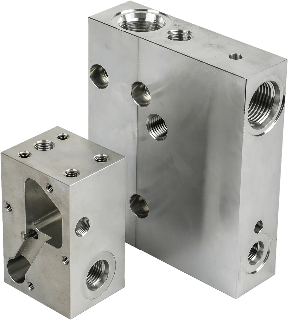 Two CNC-milled hydraulic manifold blocks with threaded ports